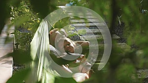 Happy mother and daughter relaxing together in a hammock at garden in summer day