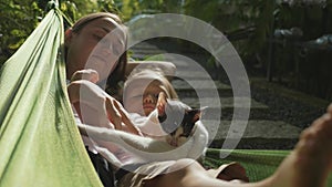 Happy mother and daughter relaxing together in a hammock at garden in summer day