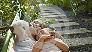 Happy mother and daughter relaxing together in a hammock at garden in summer day