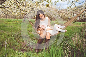 Happy mother and daughter are resting in hammock outdoors