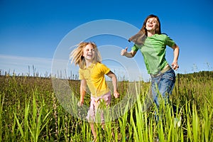 Happy mother and daughter run on field