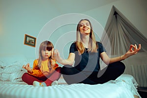 Happy Mother and Daughter Sitting in Yoga Pose at Home