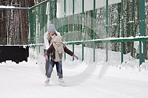 Happy mother and daughter skating on a outdoor skating rink