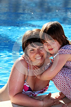 Happy mother and daughter beside a swimming pool