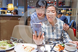 Happy mother and daughter taking  selfie during a meal in  restaurant