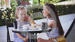 Happy mother with daughter talking eating breakfast together