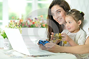 Happy mother and daughter using laptop playing video game