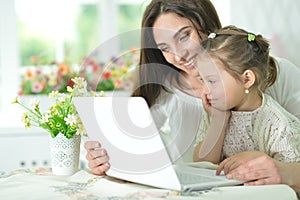 Happy mother and daughter using laptop together