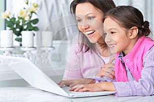 Happy mother and daughter using laptop together