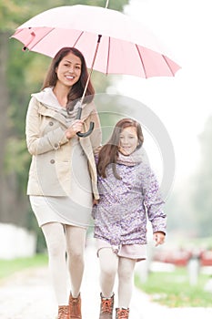 Happy mother and daughter walking in park.