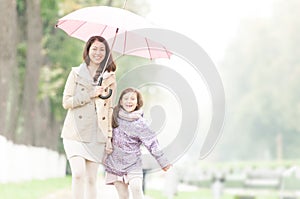 Happy mother and daughter walking in park.