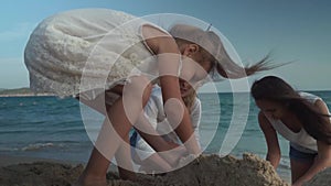 Happy mother and daughters build a sand castle on the beach of the South China Sea slow motion stock footage video