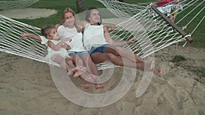 Happy mother with daughters rocking in hammock slow motion stock footage video