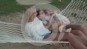 Happy mother with daughters rocking in hammock slow motion stock footage video