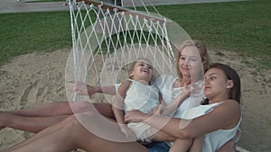 Happy mother with daughters rocking in hammock slow motion stock footage video