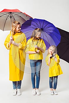 happy mother and daughters in yellow raincoats with umbrellas photo