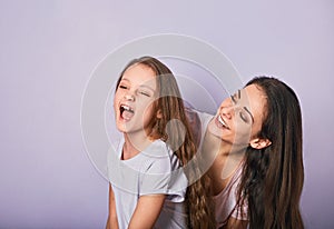 Happy mother and excited joying kid girl hugging with emotional smiling faces on purple background