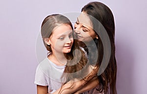Happy mother and excited joying kid girl hugging with emotional smiling faces on purple background with empty copy space