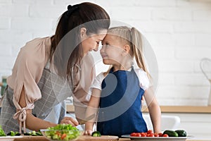 Happy mother expressing love and devotion to daughter at kitchen. photo