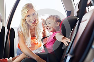 Happy mother fastening child with car seat belt photo