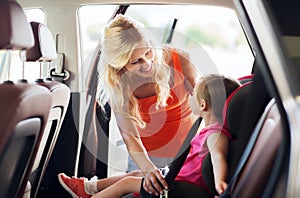 Happy mother fastening child with car seat belt