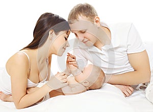 Happy mother and father with baby lying on bed