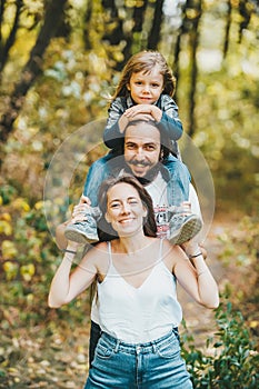 Happy mother, father and her cute son with long hair having fun rest in the autumn park. Vertical portrait