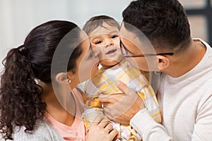 Happy mother and father kissing baby daughter