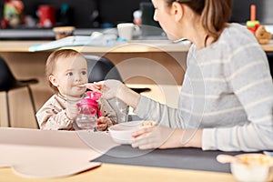 Happy mother feeding baby with puree at home