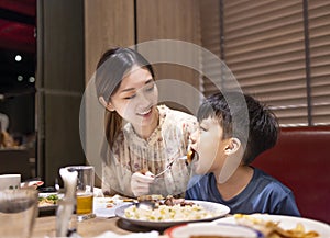Happy mother feeds her son in restaurant
