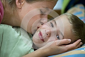 Happy mother gives her son a kiss before sleep and wish good night and beautiful dreams