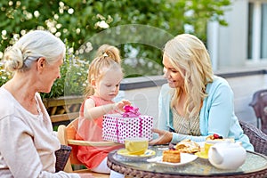 Happy mother giving present to daughter at cafe