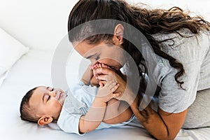 Happy mother having fun with her little baby on bed