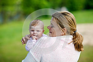 Happy mother having fun with newborn baby daughter outdoors
