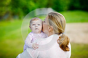 Happy mother having fun with newborn baby daughter outdoors