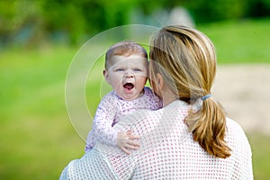 Happy mother having fun with newborn baby daughter outdoors