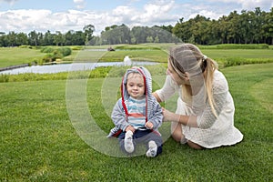 Happy mother with her 9 months old baby boy relaxing on grass at