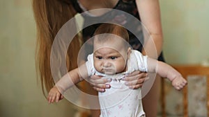 Happy mother with her baby girl learn to walk at home in the living room