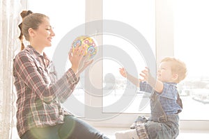 Happy mother and her baby playing colorful ball at home