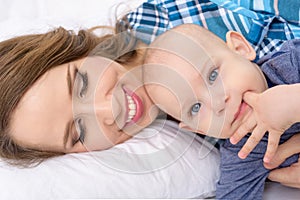 Happy mother and her baby son lying on a bed together. Happy family. Mother and newborn child.