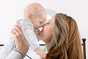 Happy mother and her baby son playing on a bed together. Happy family. Mother and newborn child.