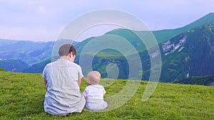 Happy mother and her child looking forward and pointing to sky. Family on trekking day in the mountains.