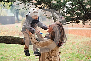 Happy mother and her child playing together in a autumn park. Happy autumn holidays. Autumn season, lifestyle