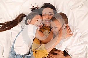 Happy mother with her children on bed, top view
