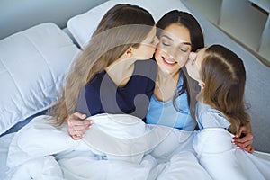 Happy mother and her children lying on a bed