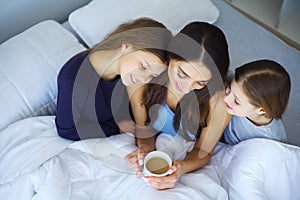 Happy mother and her children lying on a bed