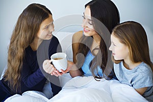 Happy mother and her children lying on a bed