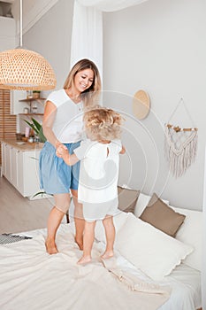 Happy mother and her daughter child girl playing and hugging in bedroom