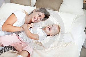 Happy mother and her daughter child girl playing and hugging in bedroom