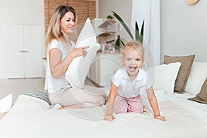 Happy mother and her daughter child girl playing and hugging in bedroom